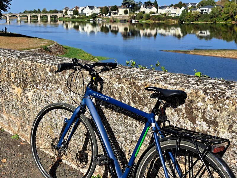 Blue bike leaning on a stone wall along a wide river