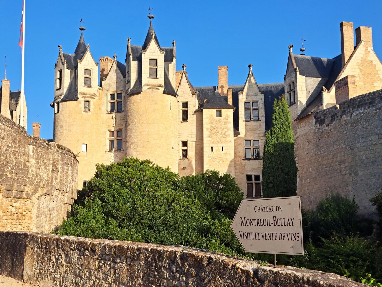 Château de Montreuil-Bellay for visits and wine sales - castle's pale limestone towers and turrets under a clear blue sky.